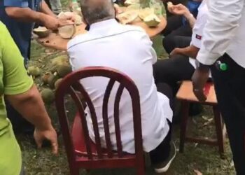 TANGKAP layar video memaparkan Mohd. Rashid Hasnon (duduk, kanan) bersama beberapa individu lain menikmati buah durian di sebuah dusun menjadi tular di media sosial di Batu Pahat, Johor.