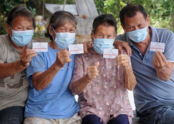 LYE Nyee Moi (dua, dari kanan) bersama anak-anaknya, Wong Yee Mooi (kiri), Wong Kit Lan (dua, dari kiri) dan Wong Kam Tim (kanan) menunjukkan kad perakuan penerimaan vaksin Covid-19 ketika ditemui pemberita di rumahnya di Kampung Sungai Sendayan, Port Dickson dekat sini hari ini.-UTUSAN/MOHD. SHAHJEHAN MAAMIN.