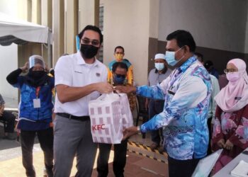WAN Ahmad Fayhsal Wan Ahmad Kamal (kiri) menyampaikan sumbangan kepada petugas PPV Dewan Dato' Zainal Abidin Zin di Bagan Serai hari ini. - UTUSAN/WAT KAMAL ABAS