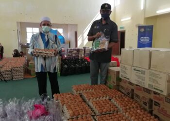 ROSOL Wahid menyampaikan barangan keperluan kepada wakil penduduk di dewan orang ramai Kampung Pasir Raja di Dungun. - UTUSAN/NIK NUR IZZATUL HAZWANI NIK ADNAN