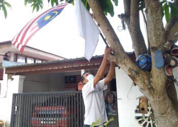 YAAKOB Montel menunjukkan bendera putih yang dipasang di hadapan rumahnya di Rumah Awam Taman Kebaya di Alor Gajah, Melaka. – UTUSAN/MUHAMMAD SHAHIZAM TAZALI