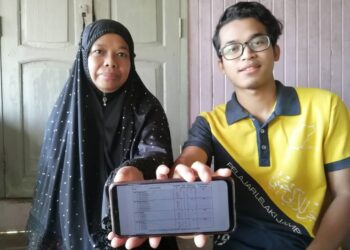 ISHAK Rukman menunjukkan keputusan Sijil Tinggi Persekolahan Malaysia (STPM) 2020 dengan ditemani ibunya, Umatillah Embong di Kampung Kuala Ping di Hulu Terengganu. - UTUSAN/NOOR HAYATI MAMAT