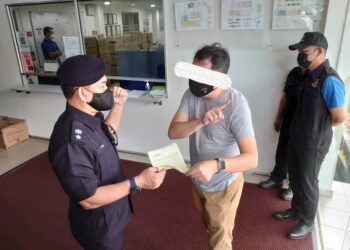 TOK Beng Yeow (kiri) menyerahkan notis kompaun kepada pemilik sebuah kilang di Kawasan Perindustrian Senai sempena Op Patuh yang dijalankan IPD Kulai di Kulai, Johor. - UTUSAN/KHAIRUL MOHD ALI