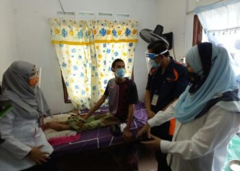YATIM Deron (dua dari kiri) yang terlantar akibat lumpuh menerima kunjungan Dr. Hazizi Abdul Yadzid dari U.N.I Klinik Bakri (dua dari kanan) dan Ahli Dewan Undangan Negeri (ADUN) Endau, Alwiyah Talib (kanan) untuk memberi suntikan vaksin di rumahnya di Perkampungan Orang Asli Tanah Abang, Mersing di Johor. - UTUSAN/MASTURAH SURADI