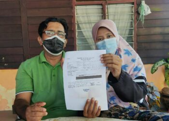 ABDUL Aziz Naina Mohamed (kiri) dan Noor Baiti Kosri menunjukkan surat pengesahan daripada hospital susulan kanser limfoma yang dihadapi Nur Aqilah Balqis. - UTUSAN/MUHAMMAD SHAHIZAM TAZALI