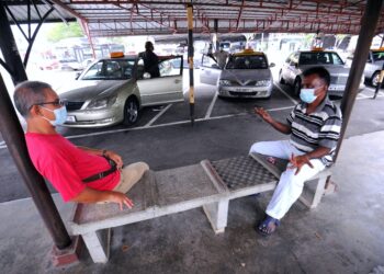 AZLAN Jamaluddin (kiri) bersama seorang rakan pemandu teksi yang lain tetap setia menunggu penumpang di Stesen Teksi Port Dickson. - UTUSAN/MOHD. SHAHJEHAN MAAMIN