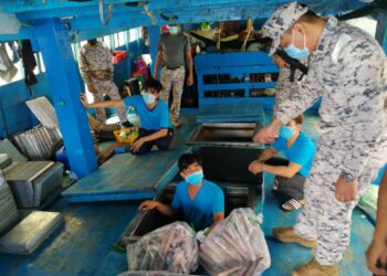 RASHIDILHADI Abd. Rashid (kanan) menunjukkan peti sejuk sebagai tempat penyimpanan hasil laut dalam sebuah bot kargo Vietnam yang ditahan di perairan Kuala Kemaman di Kemaman, Ahad lalu. -UTUSAN/
NIK NUR IZZATUL HAZWANI NIK ADNAN