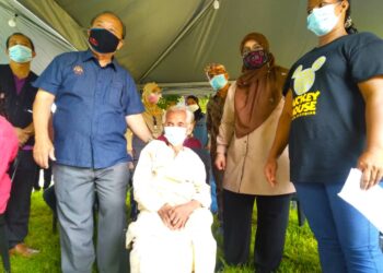 HENRY Sum Agong (kiri) dan Mas Ermieyati Samsudin (dua dari kanan) menyantuni Pucat Lobak selepas warga emas itu selesai menerima suntikan vaksin Covid-19 di Kampung Orang Asli Bukit Payung, Alor Gajah, Melaka. - UTUSAN/MUHAMMAD SHAHIZAM TAZALI