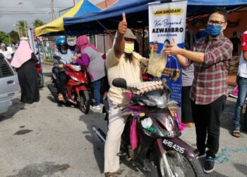 KHAIRUL Azwan Harun (kanan) ketika menjual barangan harian pada harga murah di Pasir Salak hari ini. - UTUSAN/AIN SAFRE BIDIN