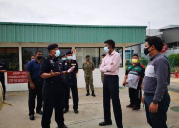 SHAMSUDIN Mamat (kiri) memperkatakan sesuatu kepada pihak pengurusan kilang Molynlycke Health Care Sdn. Bhd. yang diarahkan tutup sementara operasinya di Kuala Ketil, Baling hari ini.