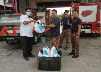 SEORANG petugas Yayasan Sofa (kiri) menyerahkan daging korban kepada anggota bomba pada program korban yayasan tersebut sempena sambutan Aidiladha sebelum ini.