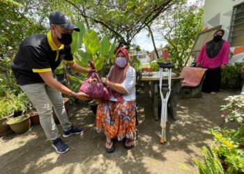 MOHAMAD Amirul Hakim menyampaikan sumbangan kepada pesakit saraf, Zainab Che Awang di Kampung Baru, Pasir Puteh, Kelantan. – UTUSAN/TOREK SULONG