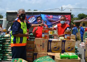 MOHD. Redzuan Md. Yusof menyerahkan sumbangan barang keperluan asas dalam Program Sumbangan Kasih Bakul Prihatin Sempena Hari Raya Aidiladha di Balai Raya Felda Palong 4, Jempol. - UTUSAN/ZAKKINA WATI AHMAD TARMIZI