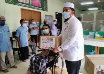 AHMAD Marzuk Shaary menyampaikan sumbangan bakul makanan kepada salah seorang penerima di Panchor, Kota Bharu. - UTUSAN/ROHANA MOHD. NAWI