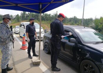 ANGGOTA polis memeriksa surat kebenaran seorang pengguna jalan raya di sekatan jalan raya (SJR) Perasing di  Lebuhraya Pantai Timur 2 (LPT 2) di Kemaman. - UTUSAN/NIK NUR IZZATUL HAZWANI NIK ADNAN