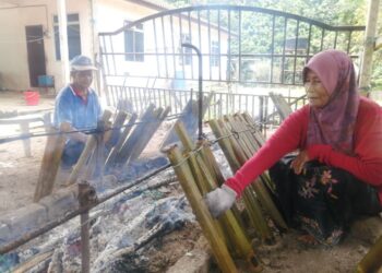 FATIMAH Mat menyiapkan tempahan lemang pada Hari Raya Aidiladha dengan dibantu suaminya, Mohamad Hassan di kediaman mereka di Kampung Kemat, Hulu Terengganu. - UTUSAN/NOOR HAYATI MAMAT