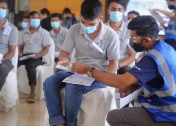 SEORANG petugas PPV PIKAS di d'Tempat Country Club, Sendayan, Seremban membantu seorang pekerja kilang mengisi borang sebelum menerima vaksin Covid-19 di PPV tersebut baru-baru ini. UTUSAN/MOHD. SHAHJEHAN MAAMIN.