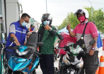 FAUZI Faizal (kiri) menuang minyak petrol ke tangki motosikal salah seorang penghantar makanan dan barangan di sebuah stesen minyak di Taman Cahaya Masai, Johor Bahru di Johor.