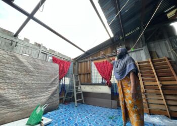 SITI Minah Mamat menunjukkan sebahagian atap ruang tamu rumahnya diterbangkan angin di Kampung Hutan Jering, Pasir Puteh, Kelantan, hari ini. - UTUSAN/TOREK SULONG