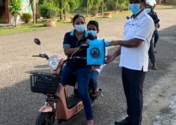 K. PATHEMANATHAN (kanan), menyerahkan peranti digital kepada pelajar, Sanjiv Edward yang ditemani ibunya, Umathevi Edward (kiri) di SMK Tebong, Alor Gajah, Melaka. - UTUSAN/MUHAMMAD SHAHIZAM TAZALI