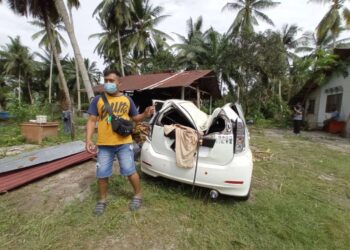 SHAZRUL Faiza Nat Noor menunjukkan kereta Perodua Myvi miliknya yang rosak teruk selepas dihempap pokok dalam kejadian di Kampung Teluk Jeri Luar di Kota Tinggi, Johor. -UTUSAN/MASTURAH SURADI