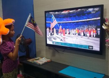 NUR Fatehah Hani Romzi dengan penuh semangat mengibarkan bendera Malaysia ketika menyaksikan pasukan kebangsaan memasuki stadium pada pembukaan Sukan Olimpik Tokyo 2020 di rumahnya di Taman Daya, Johor Bahru di Johor. - UTUSAN/RAJA JAAFAR ALI
