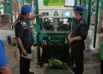 K. Muniandy (dua dari kiri) memeriksa timbangan beras di sebuah kilang di Jitra, Kubang Pasu semalam.