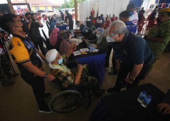 ANNUAR Musa beramah mesra dengan penduduk pada Program Vaksinasi Oghe Parlimen Terre di Kompleks Yayasan Kemiskinan Kelantan, Kota Bharu. - UTUSAN/ZULHANIFA SIDEK
