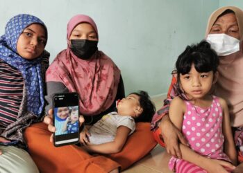 AININ Syafina Abdullah (dua dari kiri) memangku adik bongsunya berusia dua tahun menunjukkan gambar Allahyarham ibunya, Emellia Mat Husin yang meninggal dunia awal pagi ini di Kampung Bukit Depu, Kuala Terengganu.
