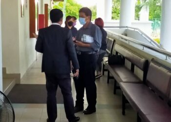 ISMAIL Ahmad yang dituduh menggunakan dokumen palsu berbual dengan peguamnya, Ahmad Dasuki Che Hasan di Mahkamah Sesyen Alor Setar hari ini. - UTUSAN/MOHD. RAFIE AZIMI