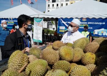 RAZMAN Zakaria (kanan) mengagihkan durian kepada petugas barisan hadapan di sekatan jalan raya (SJR) Plaza Tol Simpang Pulai, Ipoh. - UTUSAN/ZULFACHRI ZULKIFLI