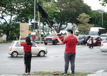 INDIVIDU yang menyertai flashmob membantah kerajaan di persimpangan lampu isyarat Jalan Sultan Azlan Shah, Ipoh. - UTUSAN/ZULFACHRI ZULKIFLI