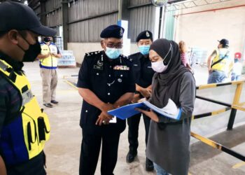 YUSUH Mat Tais (tiga kanan) memeriksa rekod kemasukan pekerja di salah sebuah kilang yang diperiksa melalui Op Patuh di Kota Kinabalu, hari ini