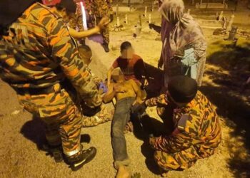 ANGGOTA bomba memberikan rawatan kepada lelaki yang cedera setelah dihempap pokok tumbang di Tanah Perkuburan Islam Parit 1, Chenderong Balai dekat Teluk Intan. - UTUSAN/IHSAN JBPM PERAK