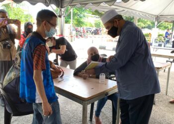 DR. IZANI (kanan) bertanyakan khabar seorang penerima vaksin Covid-19 di PPV Dewan Jubli Perak, Panji, Kota Bharu hari ini. - UTUSAN/ROSALWANI CHE SOH