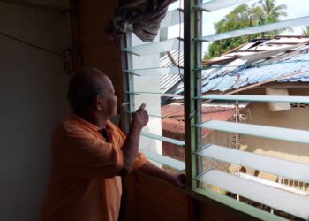ABAS Abdul Rahim menunjukkan bumbung rumahnya yang terbang ke rumah jiran dalam kejadian ribut yang melanda tiga kampung di Mentakab di Temerloh, Pahang. - FOTO/SALEHUDIN MAT RASAD
