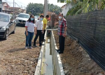 NGEH Koo Ham (kanan) menunjukkan projek menaik taraf longkang yang didakwa membazir di Taman Dinding, Ayer Tawar dekat Lumut hari ini.