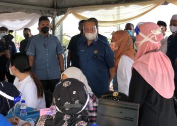 MUHYIDDIN Yassin (tengah) melawat PPV bergerak yang dikendalikan di Felda Batu 27 Lenga di Pagoh, Muar di Johor. - UTUSAN/NUR ALINA HASSAN