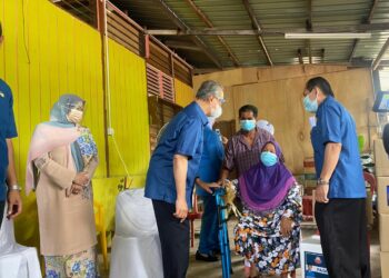 MUHYIDDIN Yassin beramah mesra ketika menyampaikan sumbangan kepada Asmah Abu Bakar di kediamannya di Batu 23, Lenga, Pagoh, di Johor. - UTUSAN/NUR ALINA HASSAN