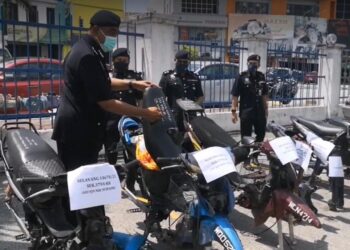 ZAINAL Mohamed (kiri) menunjukkan motosikal dirampas polis di Balai Polis Rawang.