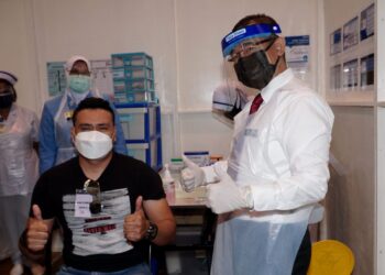 NOOR Azmi Ghazali (kanan) menunjukkan isyarat bagus selepas memberi suntikan kepada penerima vaksin Covid-19 di PPV Dewan KEMAS di Gopeng hari ini. - UTUSAN/ZULFACHRI ZULKIFLI