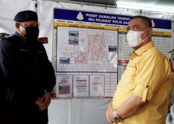 SAARANI Mohamad (kanan) mendengar taklimat mengenai PKPD yang dikuatkuasakan di Taman Meru 2B di Ipoh hari ini. - UTUSAN/ZULFACHRI ZULKIFLI