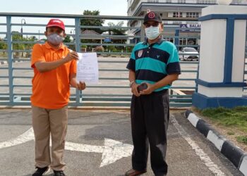 MOHD. Ikhmal Mohd Iskandar (kiri) bersama Pegawai Khas Ahli Parlimen Lumut, Abdul Razak Nazri menunjukkan laporan polis terhadap Perdana Menteri di IPD Manjung, Seri Manjung hari ini. - UTUSAN/SHAMSUL KAMAL AMARUDIN