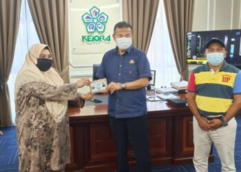 CHE Zakaria Mohd. Salleh (tengah) menyerahkan sumbangan kepada Bendahari Jawatankuasa Pembangunan dan Keselamatan Kampung (JPKK) Felda Air Tawar 5, Salabiah Mohd. Said untuk program vaksinasi berkelompok di Pejabat Kejora, Bandar Penawar, Kota Tinggi di Johor.