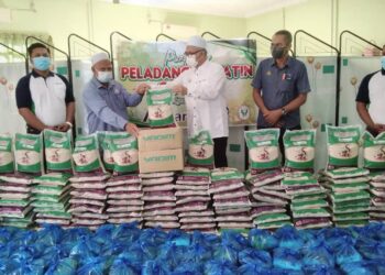 RAZMAN Zakaria (tengah) menyerahkan sumbangan barangan keperluan asas kepada Pengerusi PPK Gunung Semanggol Selinsing, Abdul Rahman Hamid di PPK Semanggol Selinsing dekat Bagan Serai. - UTUSAN/WAT KAMAL ABAS