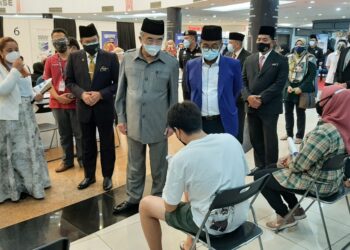MOHD. Ali Mohd. Rustam (tengah) bertanyakan sesuatu kepada salah seorang penerima vaksin di PPVIN menerusi Rivac di Dataran Pahlawan Melaka Megamall, Melaka. - UTUSAN/AMRAN MULUP