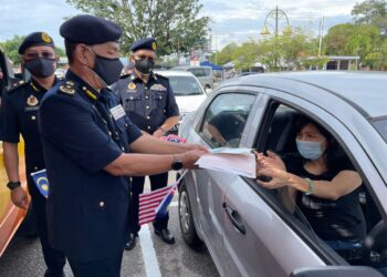 ADENAN Md. Isa menyerahkan dokumen memperbaharui lesen kenderaan kepada pelanggan di kaunter bergerak di pekarangan Ibu Pejabat JPJ di Seberang Jaya, Pulau Pinang hari ini. -UTUSAN/SITI NUR MAS ERAH AMRAN