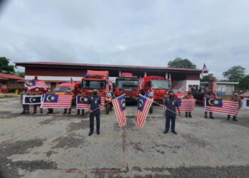 AZMAN Alias (depan, kanan) mengibarkan Jalur Gemilang bersama pegawai dan anggota Balai Bomba dan Penyelamat (BBP) Chukai di Kemaman, hari ini. - NIK NUR IZZATUL HAZWANI NIK ADNAN