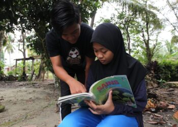 MOHAMAD Shafie Mohd. Yussof membantu adiknya, Noor Ismawati belajar. Kedua-dua mereka kini tinggal bersama ibu saudara di Kampung Lakai, Jelebu. – UTUSAN/AFIFI HAFIZ MOHD. NOR