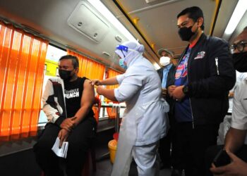 MOHD. Hafiz Ahmad (dua dari kanan) menyaksikan seorang penduduk kampung menerima suntikan sempena Program Imunisasi Outreach Vaksinasi Covid-19 di Dewanraya Kampung Sungai Melayu, di Iskandar Puteri di Johor. -UTUSAN/RAJA JAAFAR ALI